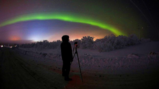 Мужчина фотографирует северное сияние на трассе Серебрянка в Мурманской области Мужчина фотографирует северное сияние на трассе Серебрянка в Мурманской области