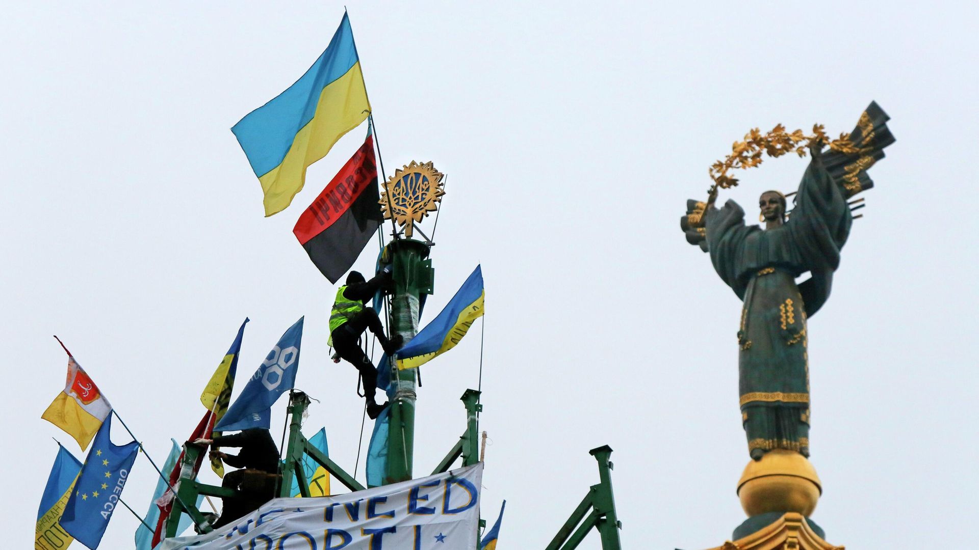 Активист проевропейского союза укрепляет украинский герб и флаг на металлической основе разрушенной елки во время митинга на площади Независимости в Киеве Активист проевропейского союза укрепляет украинский герб и флаг на металлической основе разрушенной елки во время митинга на площади Независимости в Киеве - РИА Новости, 1920, 31.12.2020