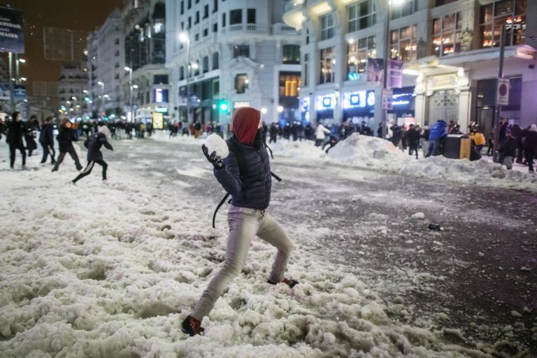 Юноша бросает снежок во время игры в снежки на площади Кальяо в Мадриде Юноша бросает снежок во время игры в снежки на площади Кальяо в Мадриде