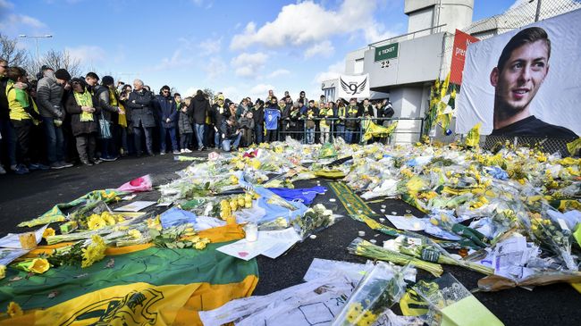 FC Nantes supporters gather in front of a portrait of late Argentinian forward Emiliano Sala to pay tribute prior to the French L1 football match between FC Nantes and Nimes Olympique at the La Beaujoire stadium in Nantes, western France on February 10, 2019. - FC Nantes football club announced on February 8, 2019 that it will freeze the #9 jersey as a tribute to Cardiff City and former Nantes footballer Emiliano Sala who died in a plane crash in the English Channel on January 21, 2019. (Photo by LOIC VENANCE / AFP)