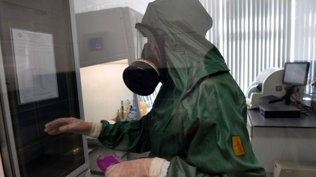 Сотрудник в костюме биозащиты за работой в вирусологической лаборатории Центра гигиены и эпидемиологии Роспотребнадзора Сотрудник в костюме биозащиты за работой в вирусологической лаборатории Центра гигиены и эпидемиологии Роспотребнадзора