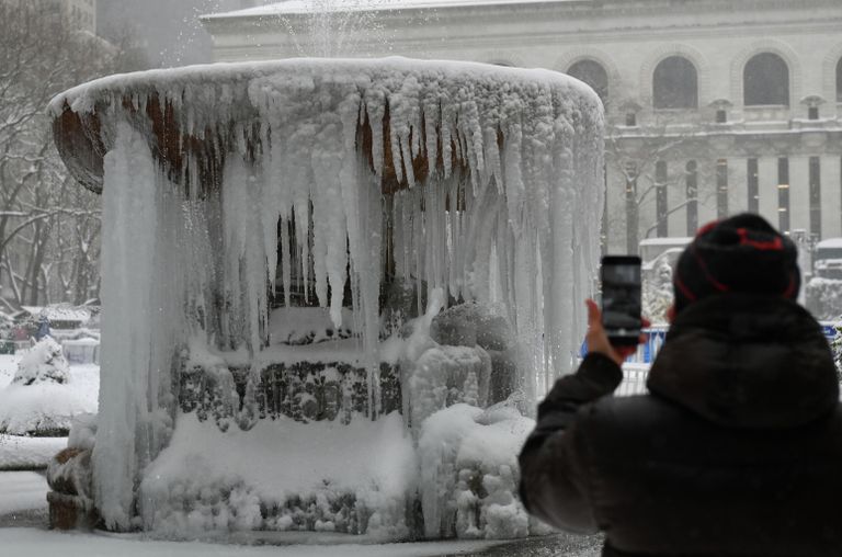 Прохожий фотографирует покрытый льдом мемориальный фонтан Жозефины Шоу Лоуэлл во время снегопада в Нью-Йорке Прохожий фотографирует покрытый льдом мемориальный фонтан Жозефины Шоу Лоуэлл во время снегопада в Нью-Йорке