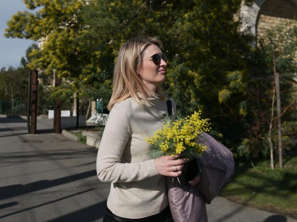 Девушка с  цветами мимозы на одной из улиц в Сочи