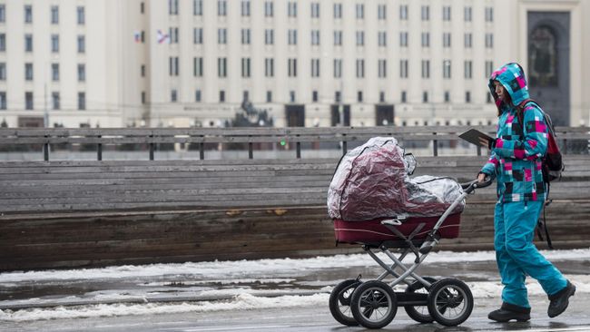 Женщина гуляет с ребенком в коляске Женщина гуляет с ребенком в коляске