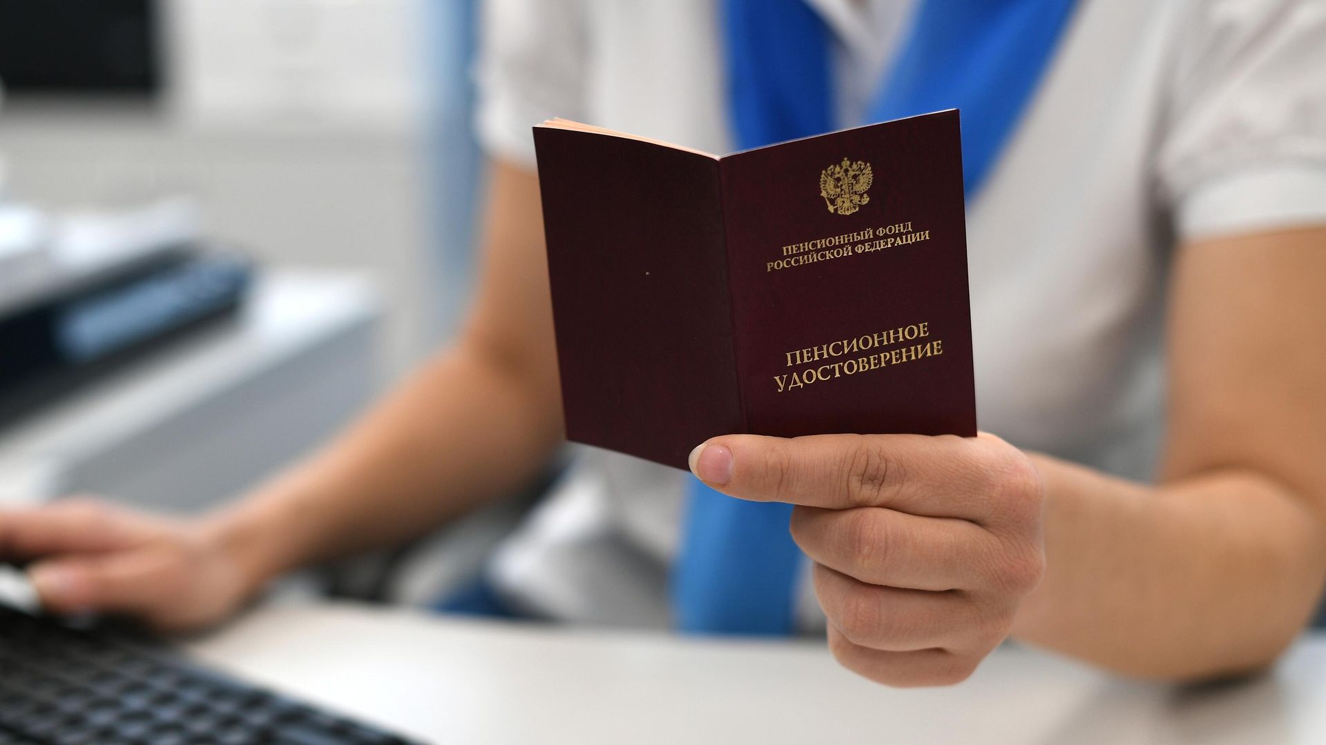 Сотрудник пенсионного фонда держит в руках пенсионное удостоверение - РИА Новости, 1920, 16.09.2021