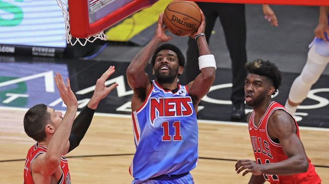 CHICAGO, ILLINOIS - APRIL 04: Kyrie Irving #11 of the Brooklyn Nets shoots between Nikola Vucevic #9 (L) and Patrick Williams #44 of the Chicago Bulls at the United Center on April 04, 2021 in Chicago, Illinois. The Bulls defeated the Nets 115-107. NOTE TO USER: User expressly acknowledges and agrees that, by downloading and or using this photograph, User is consenting to the terms and conditions of the Getty Images License Agreement.   Jonathan Daniel/Getty Images/AFP (Photo by JONATHAN DANIEL / GETTY IMAGES NORTH AMERICA / Getty Images via AFP)