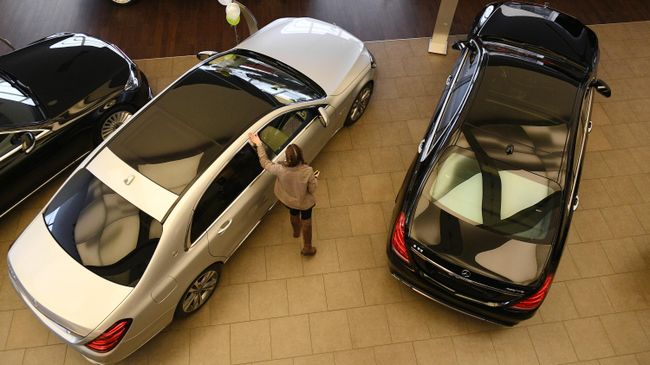 Менеджер демонстрирует покупателям автомобиль в автосалоне