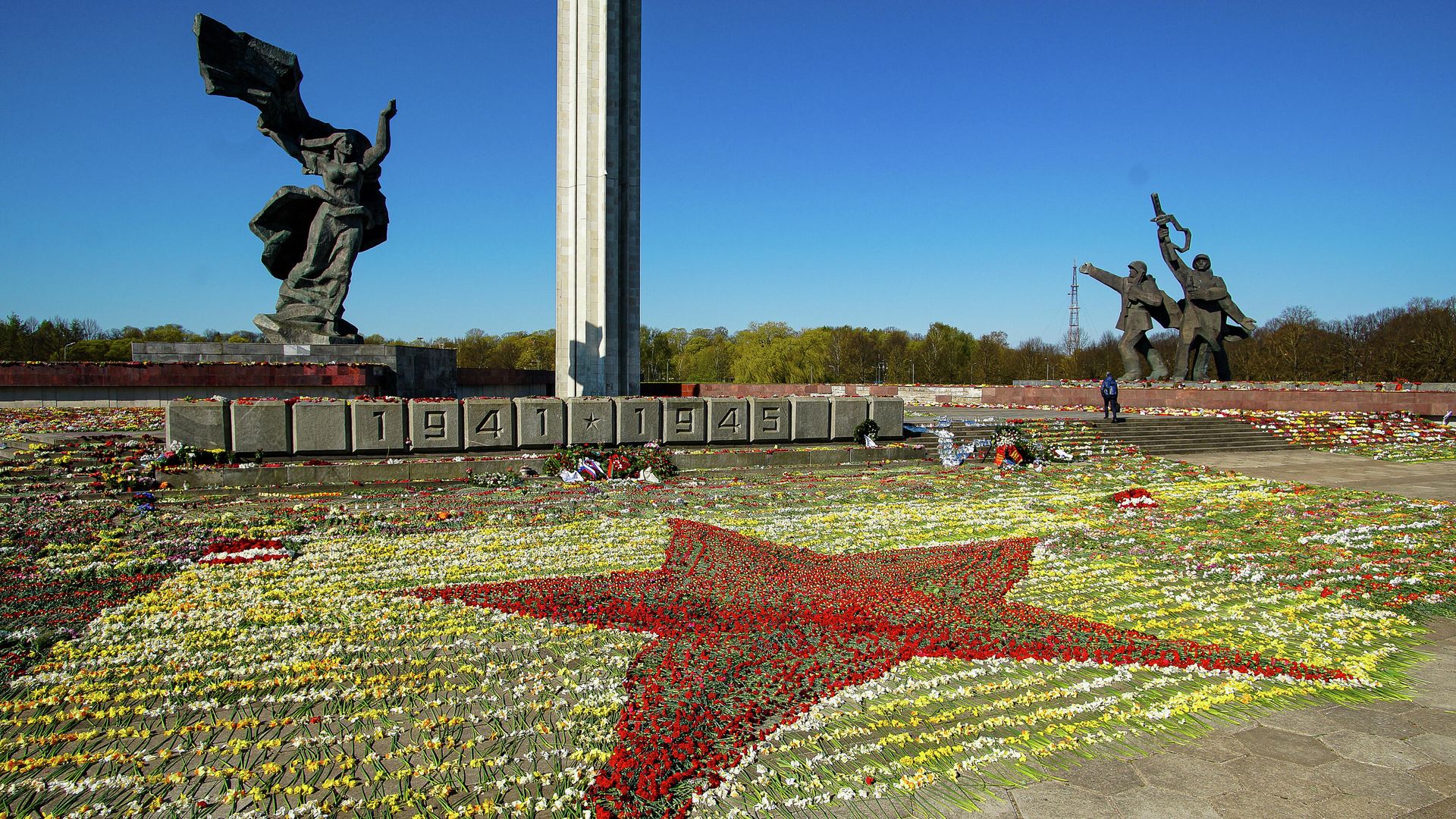Красная звезда, выложенная волонтерами из цветов, возложенных к памятнику Освободителям в Парке Победы в Риге Красная звезда, выложенная волонтерами из цветов, возложенных к памятнику Освободителям в Парке Победы в Риге - РИА Новости, 1920, 10.05.2021