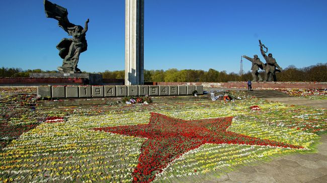 Красная звезда, выложенная волонтерами из цветов, возложенных к памятнику Освободителям в Парке Победы в Риге Красная звезда, выложенная волонтерами из цветов, возложенных к памятнику Освободителям в Парке Победы в Риге
