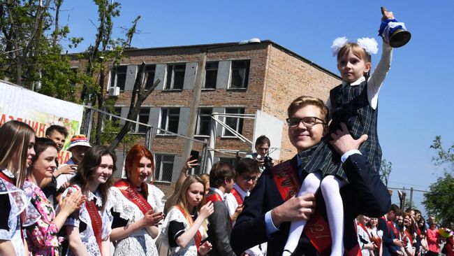 Выпускник несет школьницу с колокольчиком во время последнего звонка в гимназии №2 во Владивостоке