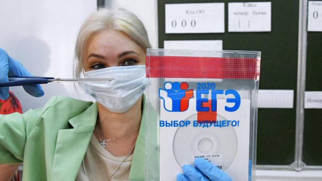Учительница вскрывает конверт с диском, в котором содержатся задания для единого государственного экзамена по русскому языку, перед началом ЕГЭ по русскому языку