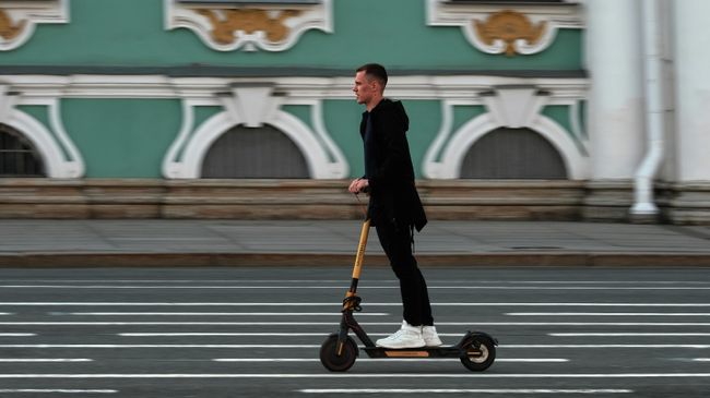 Мужчина едет на самокате по Дворцовой площади в Санкт-Петербурге Мужчина едет на самокате по Дворцовой площади в Санкт-Петербурге