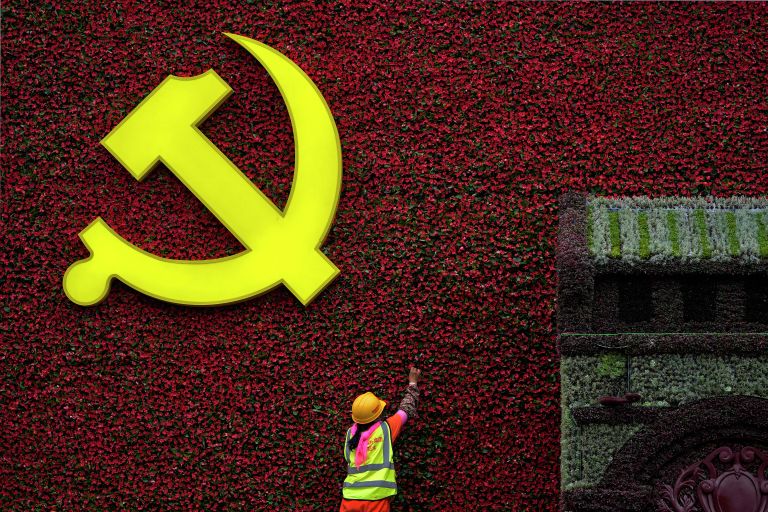 Рабочий устанавливает цветочное украшение в форме флага с символом Коммунистической партии в Пекине Рабочий устанавливает цветочное украшение в форме флага с символом Коммунистической партии в Пекине