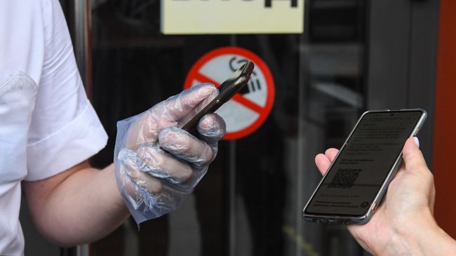 Сотрудник сканирует QR-код у входа в ресторан McDonald's в Москве Сотрудник сканирует QR-код у входа в ресторан McDonald's в Москве