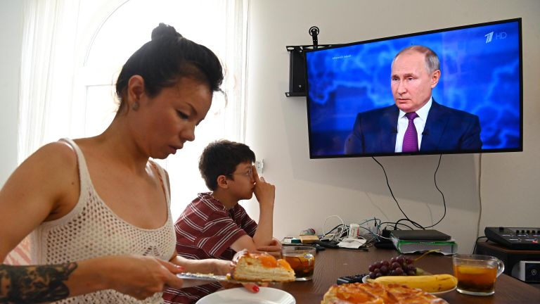 Женщина с ребенком смотрят трансляцию прямой линии с президентом РФ Владимиром Путиным Женщина с ребенком смотрят трансляцию прямой линии с президентом РФ Владимиром Путиным