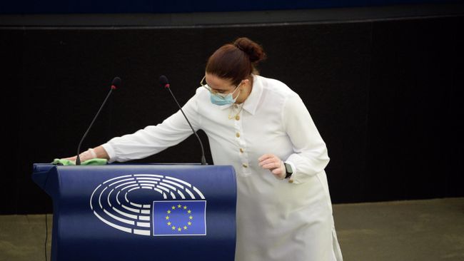 Сотрудница дезинфицирует трибуну после выступления депутатов на пленарной сессии Европейского парламента в Страсбурге