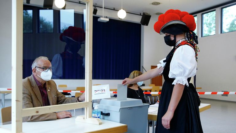 Женщина в традиционном костюме голосует в Шварцвальде, Германия Женщина в традиционном костюме голосует в Шварцвальде, Германия