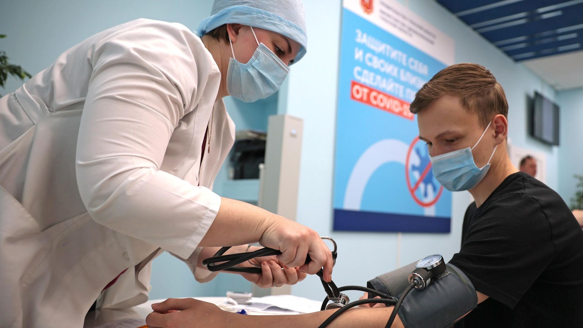 Медицинский работник измеряет давление молодому человеку перед вакцинацией - РИА Новости, 1920, 22.10.2021