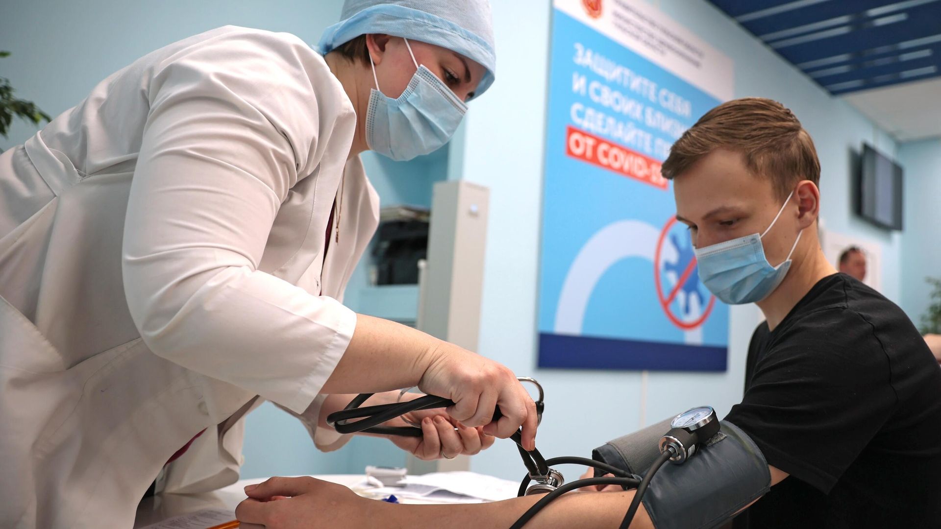 Медицинский работник измеряет давление молодому человеку перед вакцинацией Медицинский работник измеряет давление молодому человеку перед вакцинацией - РИА Новости, 1920, 21.10.2021