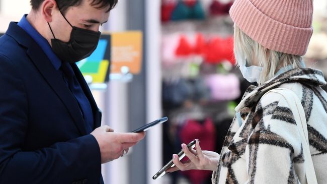 Сотрудник службы безопасности проверяет наличие у посетительницы QR-кода на входе в торговый центр