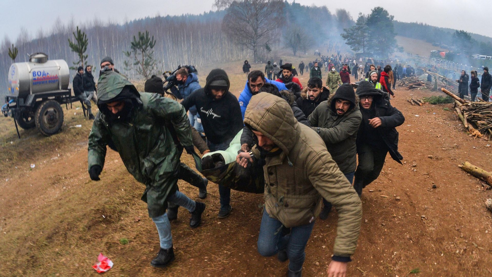 Мужчины несут к машине скорой помощи женщину в лагере нелегальных мигрантов на белорусско-польской границе Мужчины несут к машине скорой помощи женщину в лагере нелегальных мигрантов на белорусско-польской границе - РИА Новости, 1920, 14.11.2021