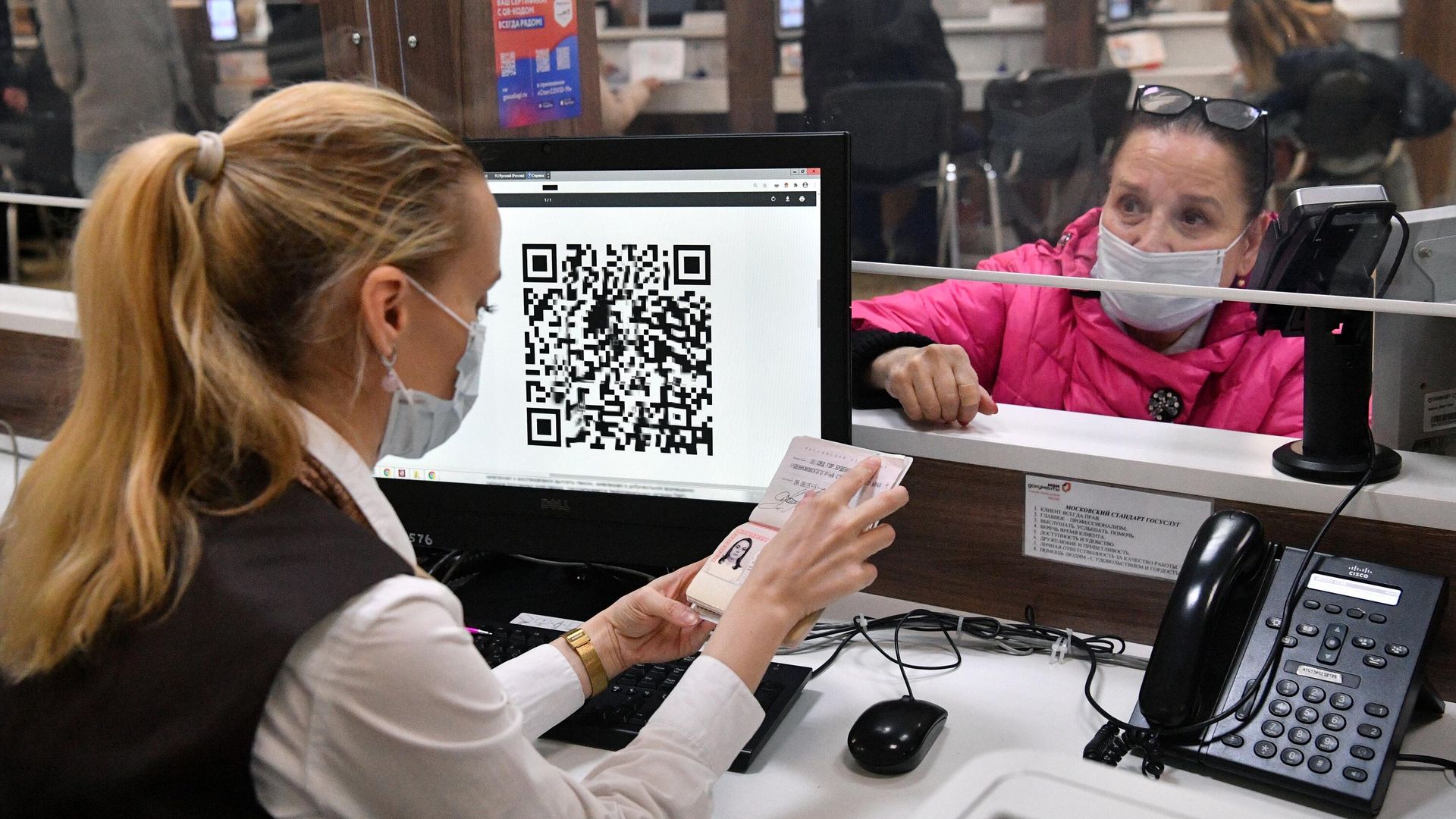 Сотрудница МФЦ проверяет документы у женщины для выдачи ей распечатанного бумажного QR-кода Сотрудница МФЦ проверяет документы у женщины для выдачи ей распечатанного бумажного QR-кода - РИА Новости, 1920, 29.11.2021