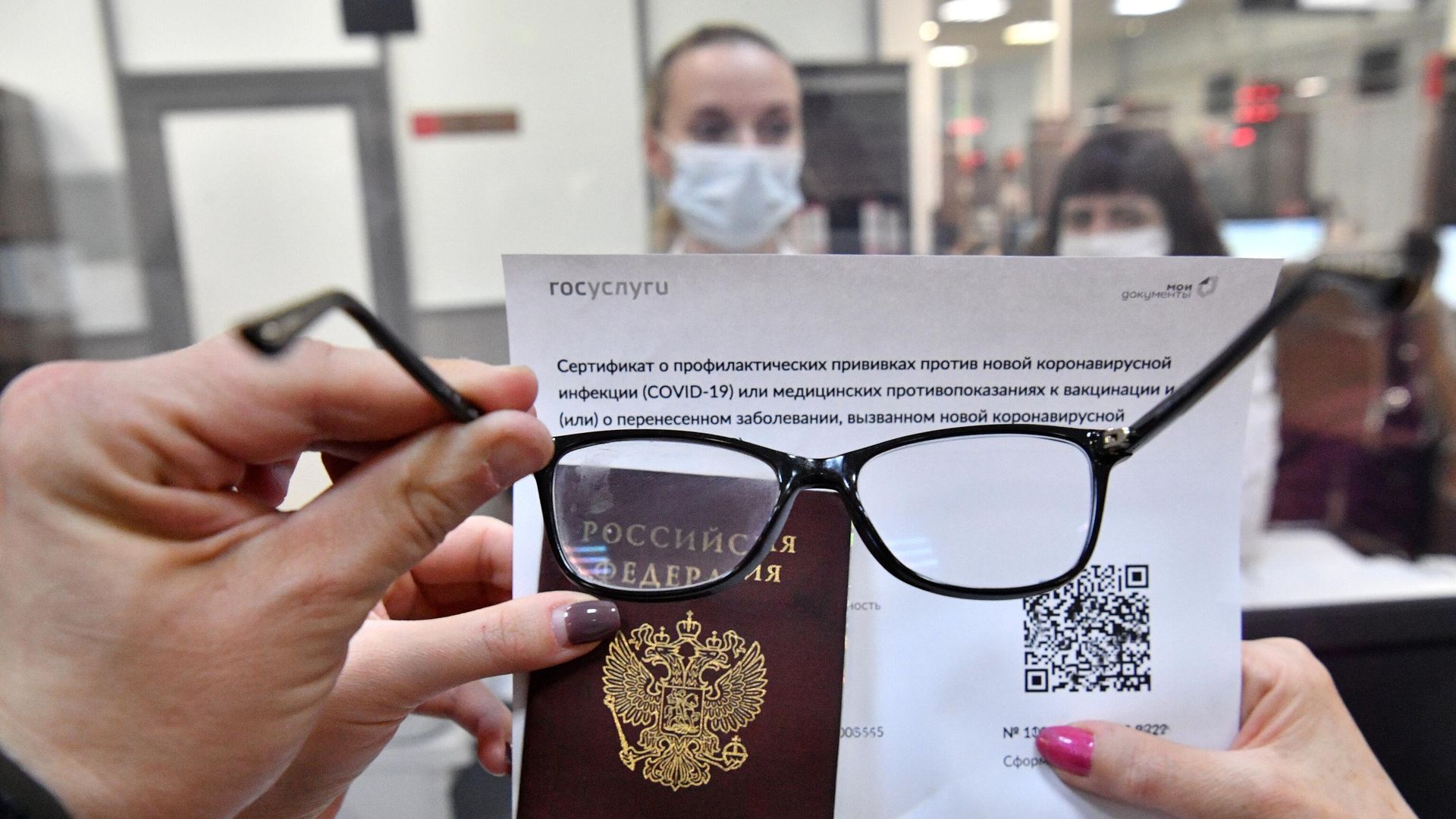 Посетитель осматривает распечатанный бумажный QR-код, полученный в многофункциональном центре госуслуг Мои документы в Москве Посетитель осматривает распечатанный бумажный QR-код, полученный в многофункциональном центре госуслуг Мои документы в Москве - РИА Новости, 1920, 13.12.2021