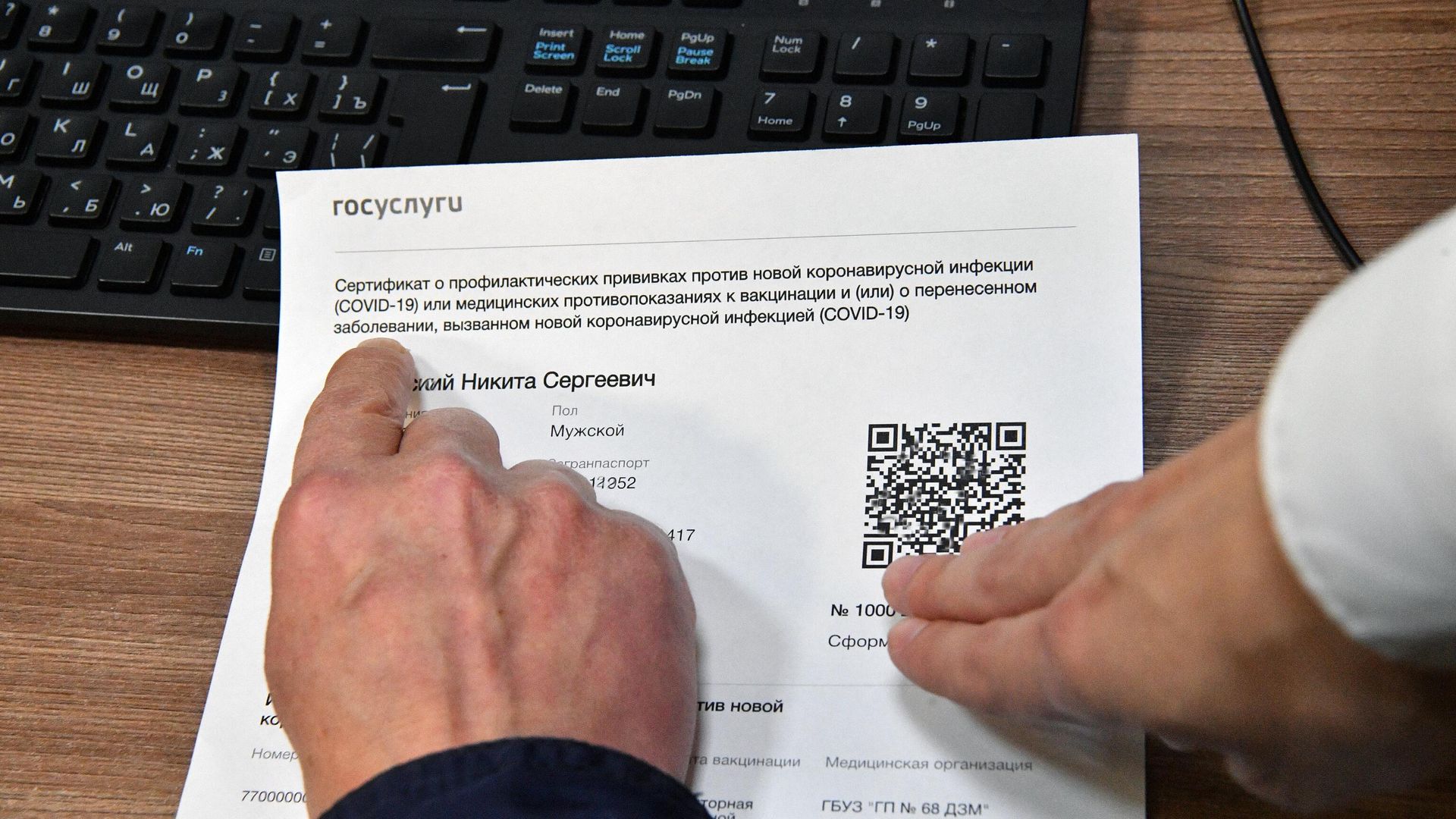 Посетитель осматривает распечатанный бумажный QR-код, полученный в многофункциональном центре госуслуг Мои документы в Москве Посетитель осматривает распечатанный бумажный QR-код, полученный в многофункциональном центре госуслуг Мои документы в Москве - РИА Новости, 1920, 14.12.2021