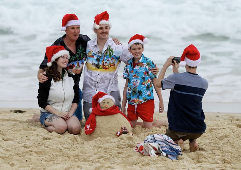 Семья фотографируется в рождественских колпаках на пляже в Сиднее, Австралия Семья фотографируется в рождественских колпаках на пляже в Сиднее, Австралия