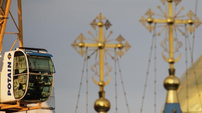Кабина строительного крана и кресты на куполах храма