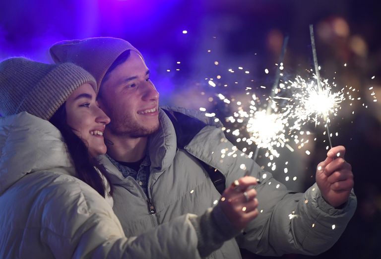 Молодые люди с бенгальскими огнями во время празднования Нового 2022 года на катке в парке Черное озеро в Казани