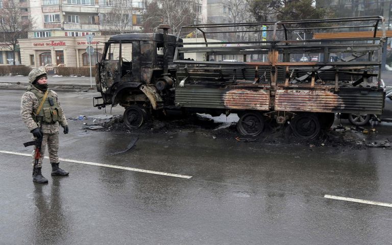 Сотрудник правоохранительных органов Казахстана возле сгоревшего грузовика в Алма-Ате Сотрудник правоохранительных органов Казахстана возле сгоревшего грузовика в Алма-Ате