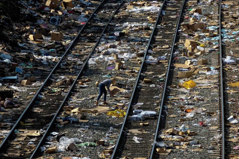 Представитель СМИ поднимает мятую коробку на железнодорожных путях Union Pacific в центре Лос-Анджелеса Представитель СМИ поднимает мятую коробку на железнодорожных путях Union Pacific в центре Лос-Анджелеса