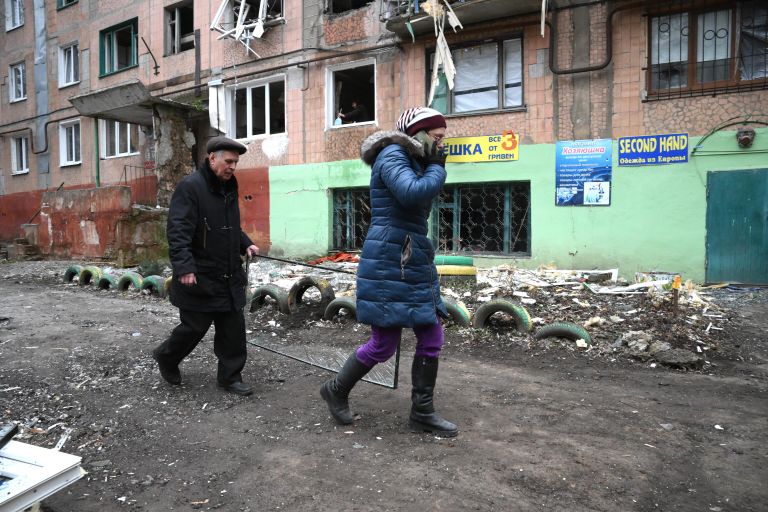 Люди идут вдоль дома, пострадавшего в результате обстрелов Горловки Люди идут вдоль дома, пострадавшего в результате обстрелов Горловки