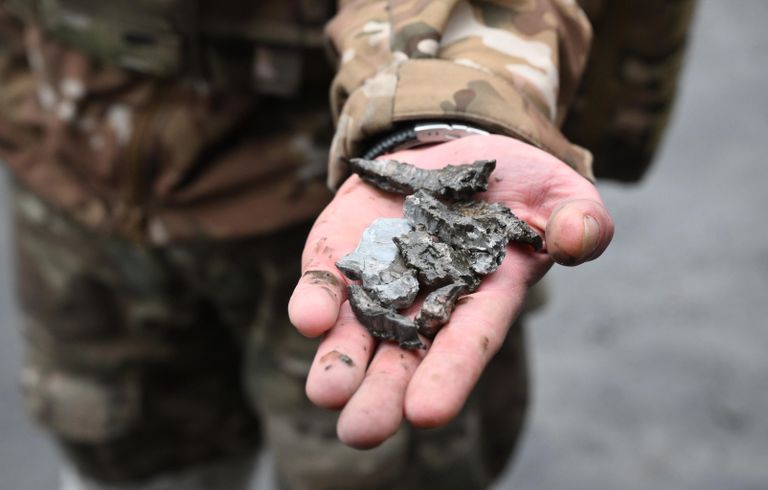 Военнослужащий демонстрирует осколки боеприпасов во дворе многоэтажного жилого дома в Донецке, поврежденного в результате обстрела Военнослужащий демонстрирует осколки боеприпасов во дворе многоэтажного жилого дома в Донецке, поврежденного в результате обстрела