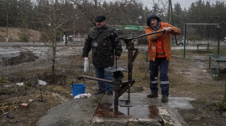 Мужчины набирают питьевую воду в различные емкости во дворе жилого дома в освобожденном городе Счастье в Луганской народной республике Мужчины набирают питьевую воду в различные емкости во дворе жилого дома в освобожденном городе Счастье в Луганской народной республике