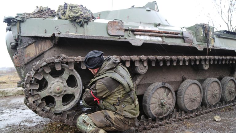 Военнослужащий армии ДНР чинит бронетехнику на дороге в селе Бугас Военнослужащий армии ДНР чинит бронетехнику на дороге в селе Бугас