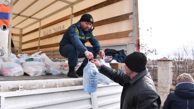 Сотрудник МЧС ДНР передает бутыли воды и продуктовый набор из гуманитарной помощи жителю села Бугас