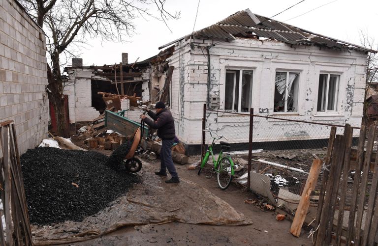 Мужчина разгружает тележку с углем у разрушенного дома в селе Талаковка в Донецкой народной республике Мужчина разгружает тележку с углем у разрушенного дома в селе Талаковка в Донецкой народной республике