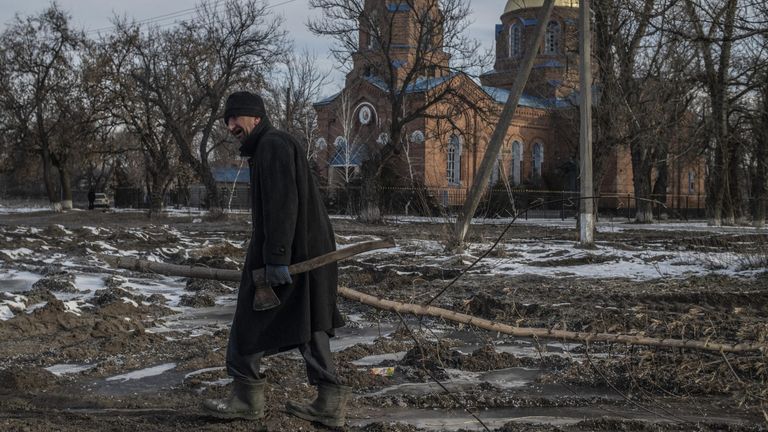 Мужчина несет срубленную ветку дерева в поселке Трехизбенка в Луганской народной республике Мужчина несет срубленную ветку дерева в поселке Трехизбенка в Луганской народной республике