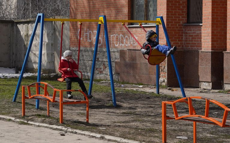 Дети качаются на качелях во дворе жилого дома в станице Луганской в Луганской народной республике Дети качаются на качелях во дворе жилого дома в станице Луганской в Луганской народной республике