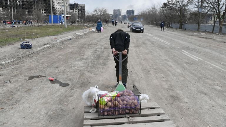 Мужчина везет тележку с продуктами на дороге в Мариуполе Мужчина везет тележку с продуктами на дороге в Мариуполе