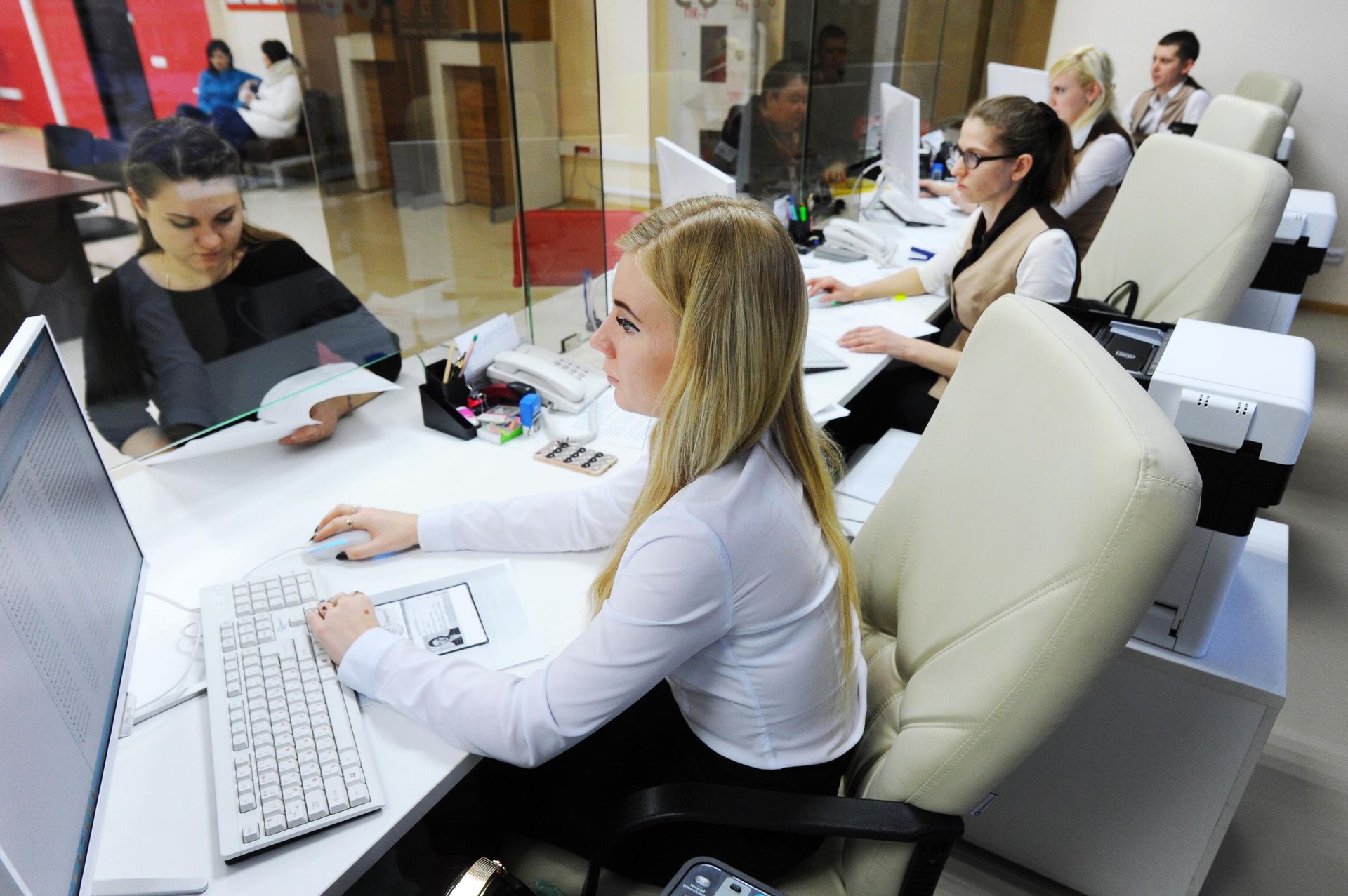 Сотрудники МФЦ за работой с заявителями в зоне обслуживания Сотрудники МФЦ за работой с заявителями в зоне обслуживания - РИА Новости, 1920, 22.03.2022