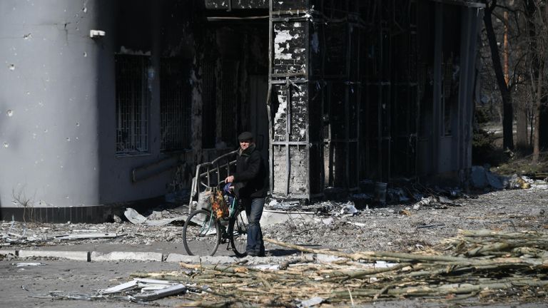 Мужчина с велосипедом во дворе разрушенного в результате обстрелов жилого дома в Мариуполе