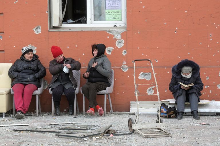 Жители Мариуполя проводят время снаружи, во дворе разрушенного дома Жители Мариуполя проводят время снаружи, во дворе разрушенного дома