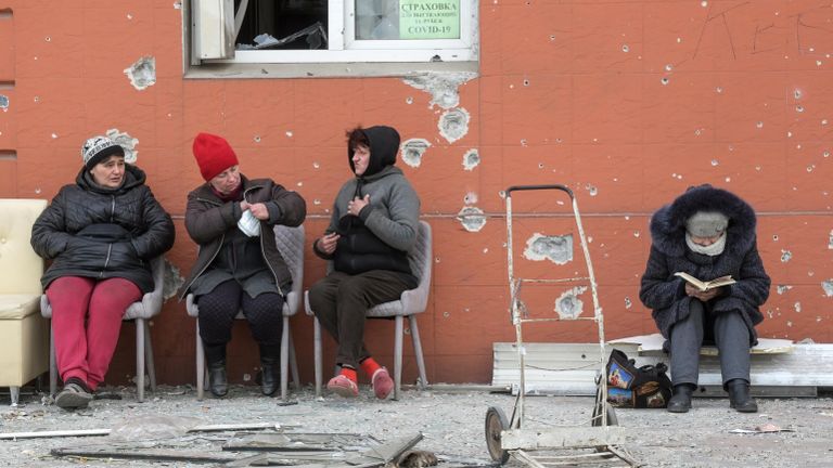 Жители Мариуполя проводят время снаружи, во дворе разрушенного дома Жители Мариуполя проводят время снаружи, во дворе разрушенного дома