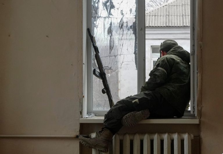 Военнослужащий ДНР сидит у окна во время боестолкновений в Левобережном районе Мариуполя Военнослужащий ДНР сидит у окна во время боестолкновений в Левобережном районе Мариуполя