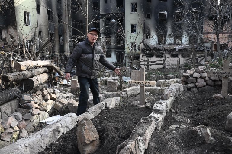 Местный житель у могилы во дворе разрушенного дома в Мариуполе Местный житель у могилы во дворе разрушенного дома в Мариуполе