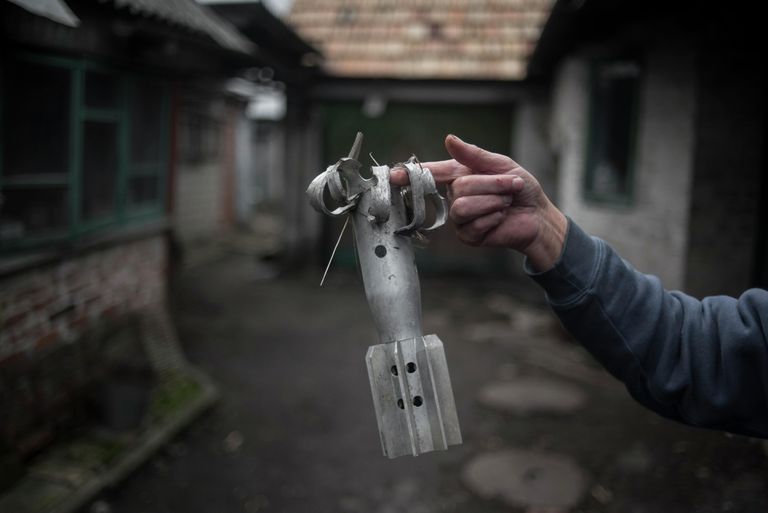 Женщина демонстрирует осколок мины во дворе жилого дома в поселке Зайцево Донецкой области. Женщина демонстрирует осколок мины во дворе жилого дома в поселке Зайцево Донецкой области.