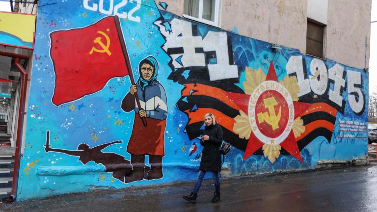Граффити с изображением бабушки с красным флагом на фасаде здания в Мурманске